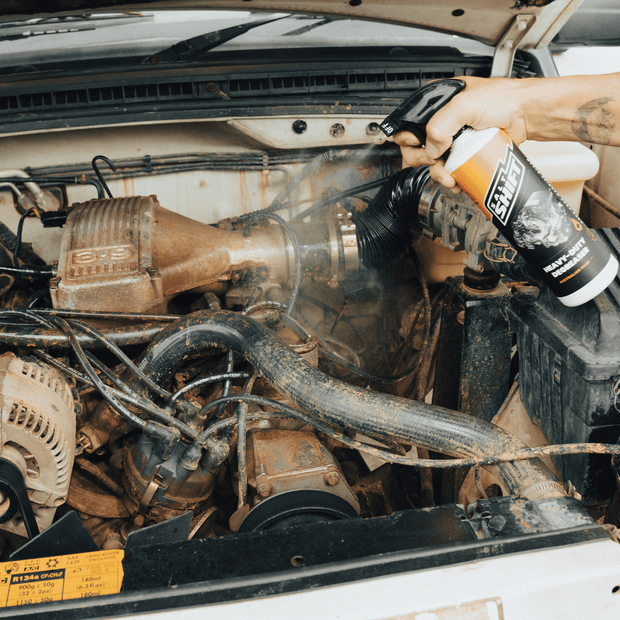 Salt Shift Heavy-Duty Degreaser being sprayed on a dirty car engine to remove grease, grime, and restore cleanliness.