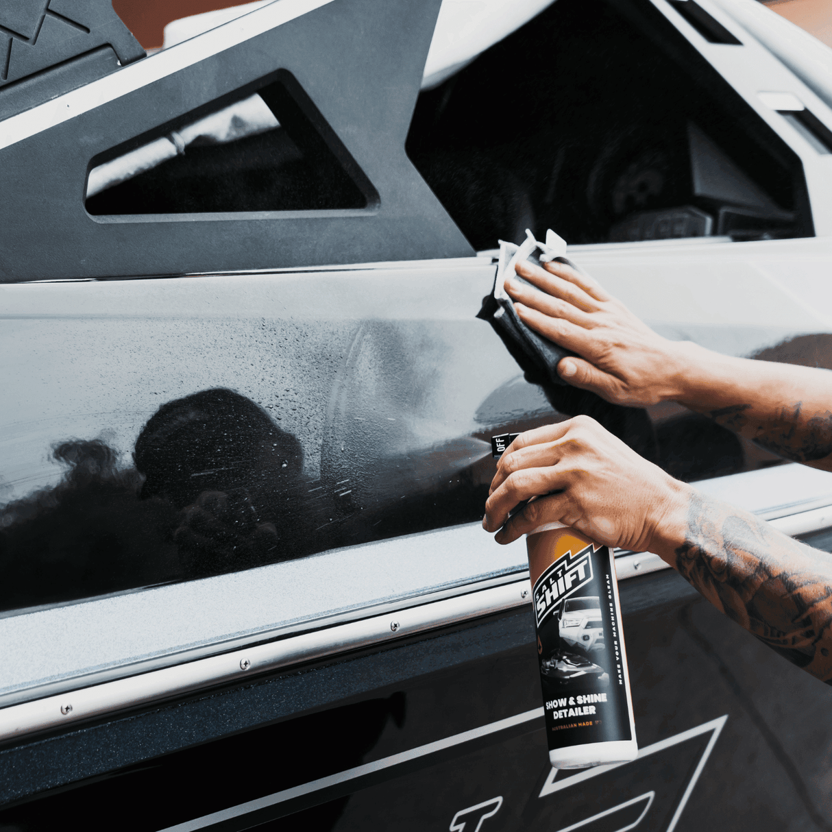 Hand applying Salt Shift Show & Shine Detailer on a black vehicle for a spotless, polished finish. Premium auto detailing spray.